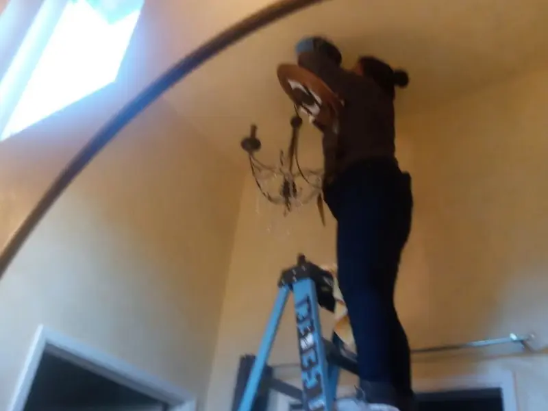 Electrician installing a chandelier in a West Lafayette residence